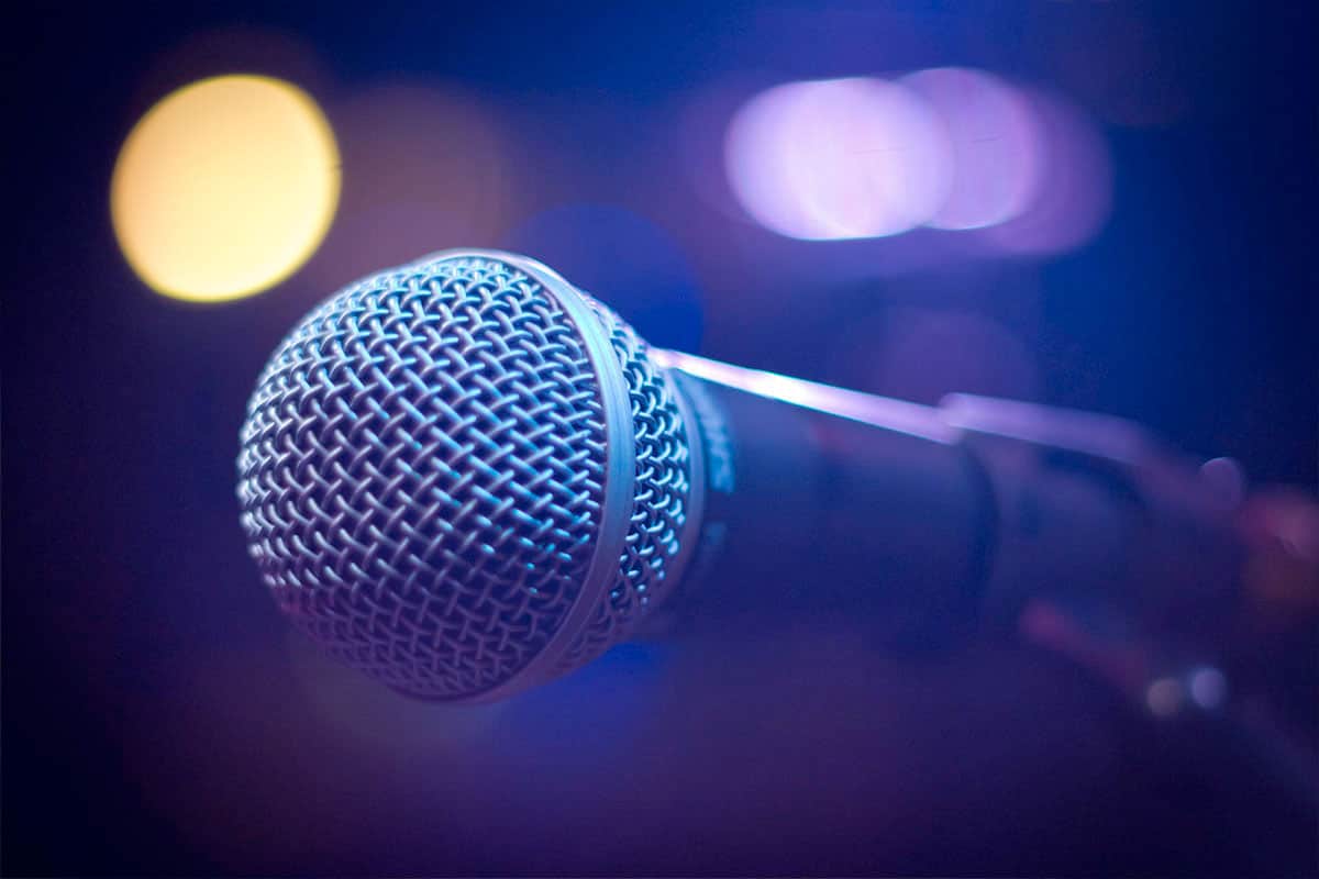 The-Keynote-Experience-Microphone-1024x683-1 keynote speaker microphone with stage lights in the purplr background